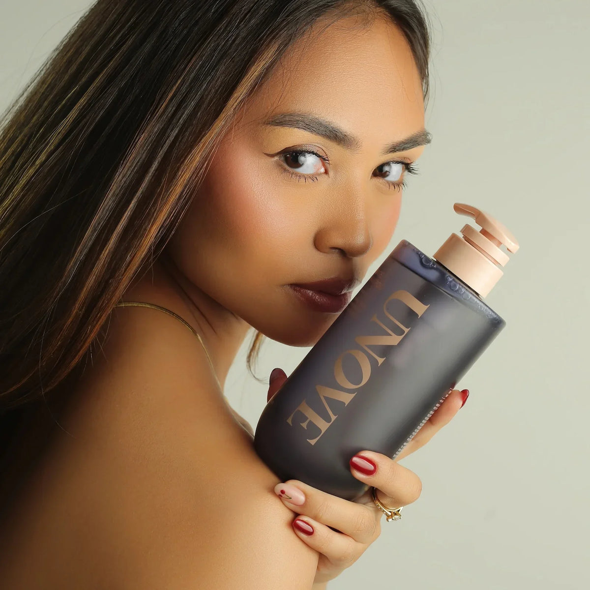 Woman holding UNOVE beauty product, showcasing radiant skin and sleek packaging for Korean skincare routine