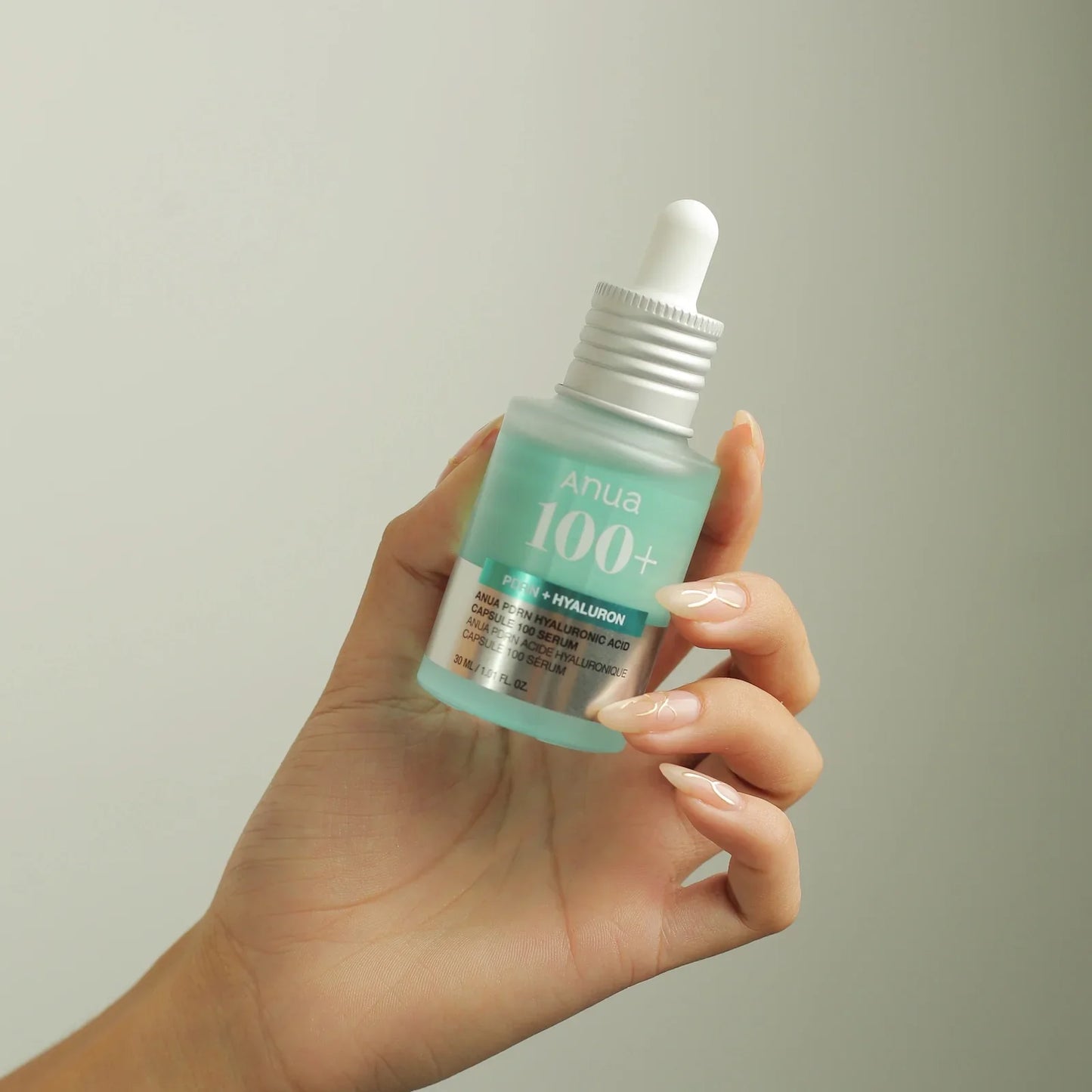 Hand holding Anua 100+ PDRN + Hyaluron serum bottle, Korean skincare for radiant skin