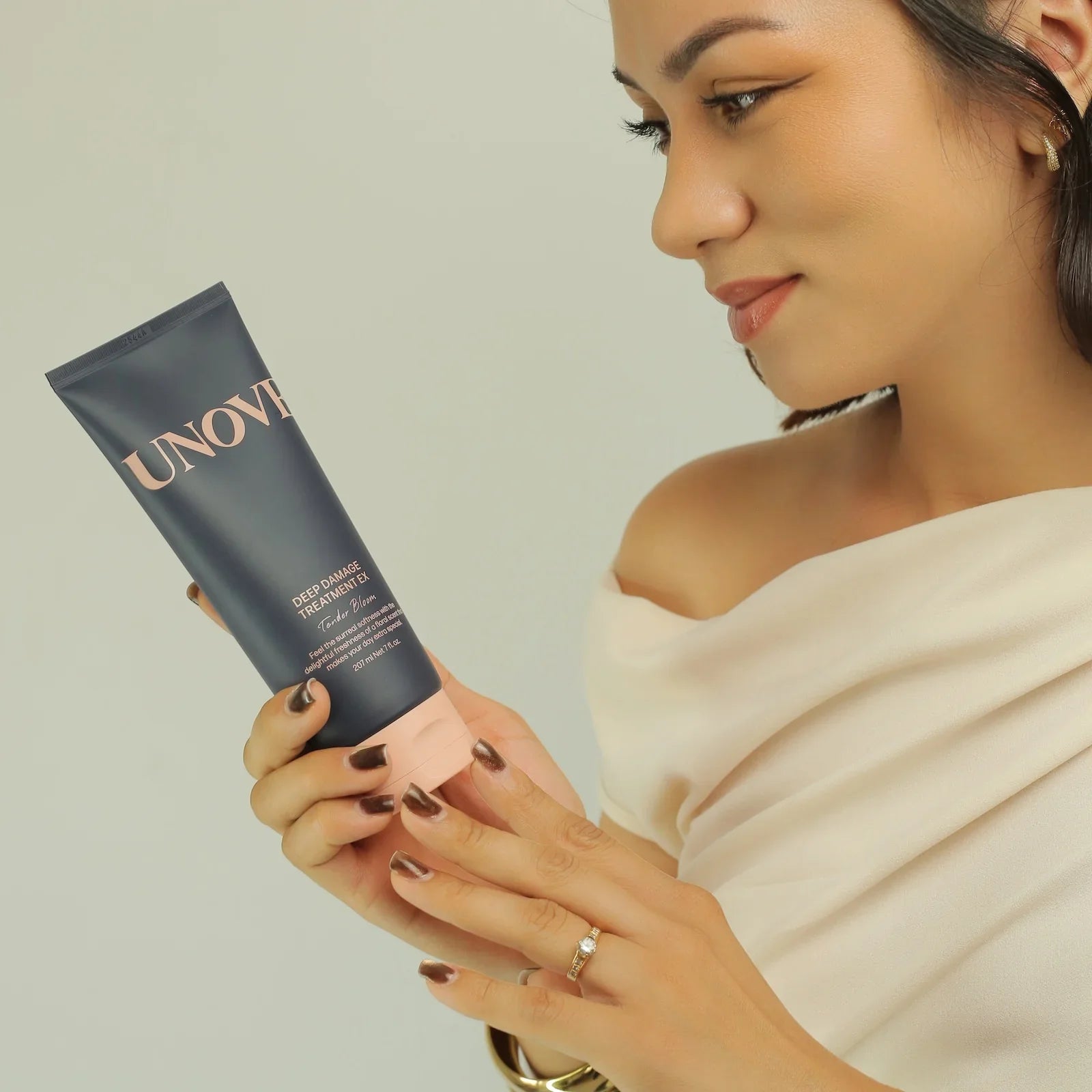 Woman holding UNOVE Deep Damage Treatment EX hair mask, Korean beauty product for repair and softness